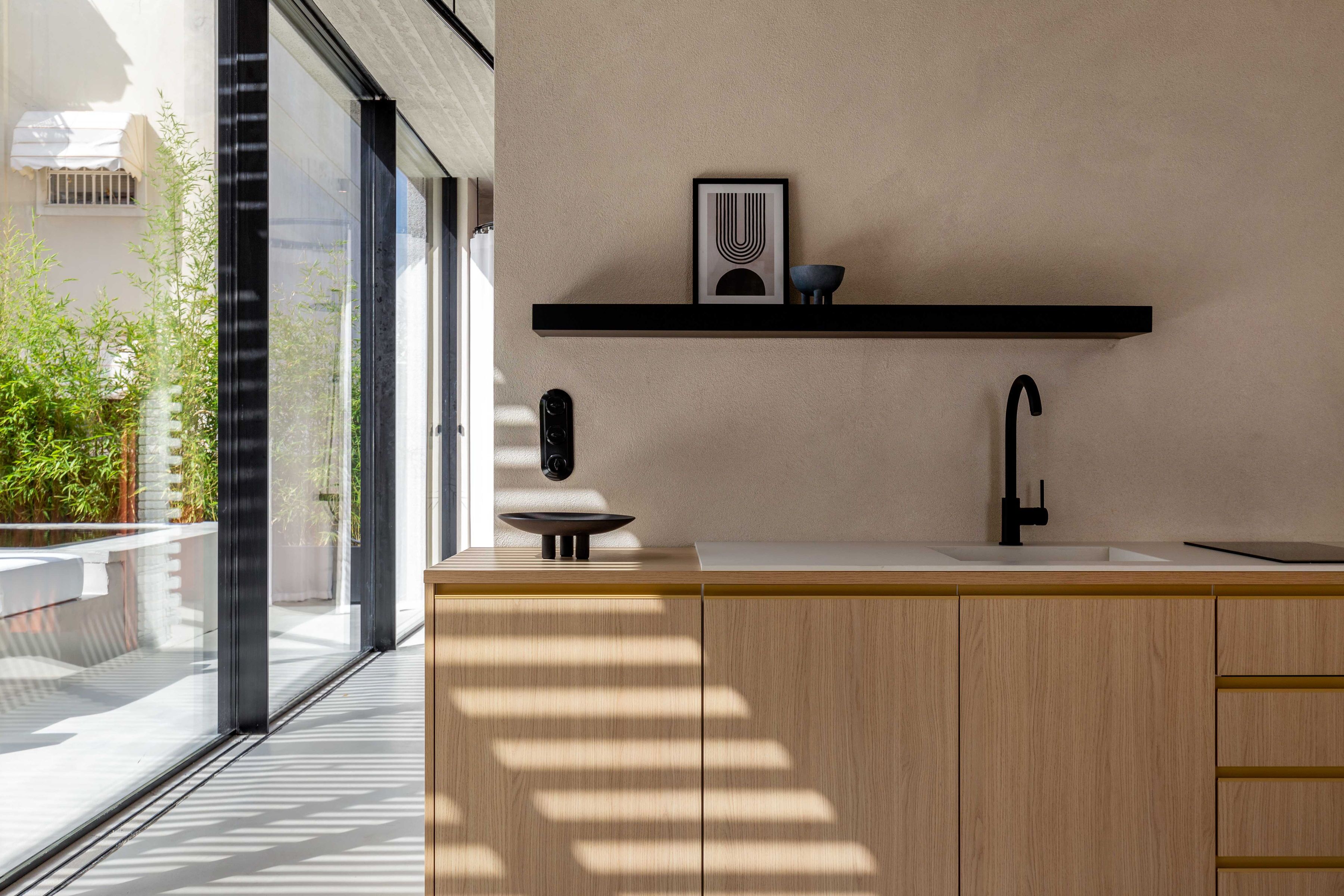 Cozinha moderna com design minimalista, destacando uma torneira preta, bancada branca e armário de madeira.