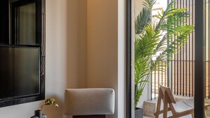 A modern interior with a sofa, a small round table, and a large potted plant. - The Newel Psychiko (Athens)