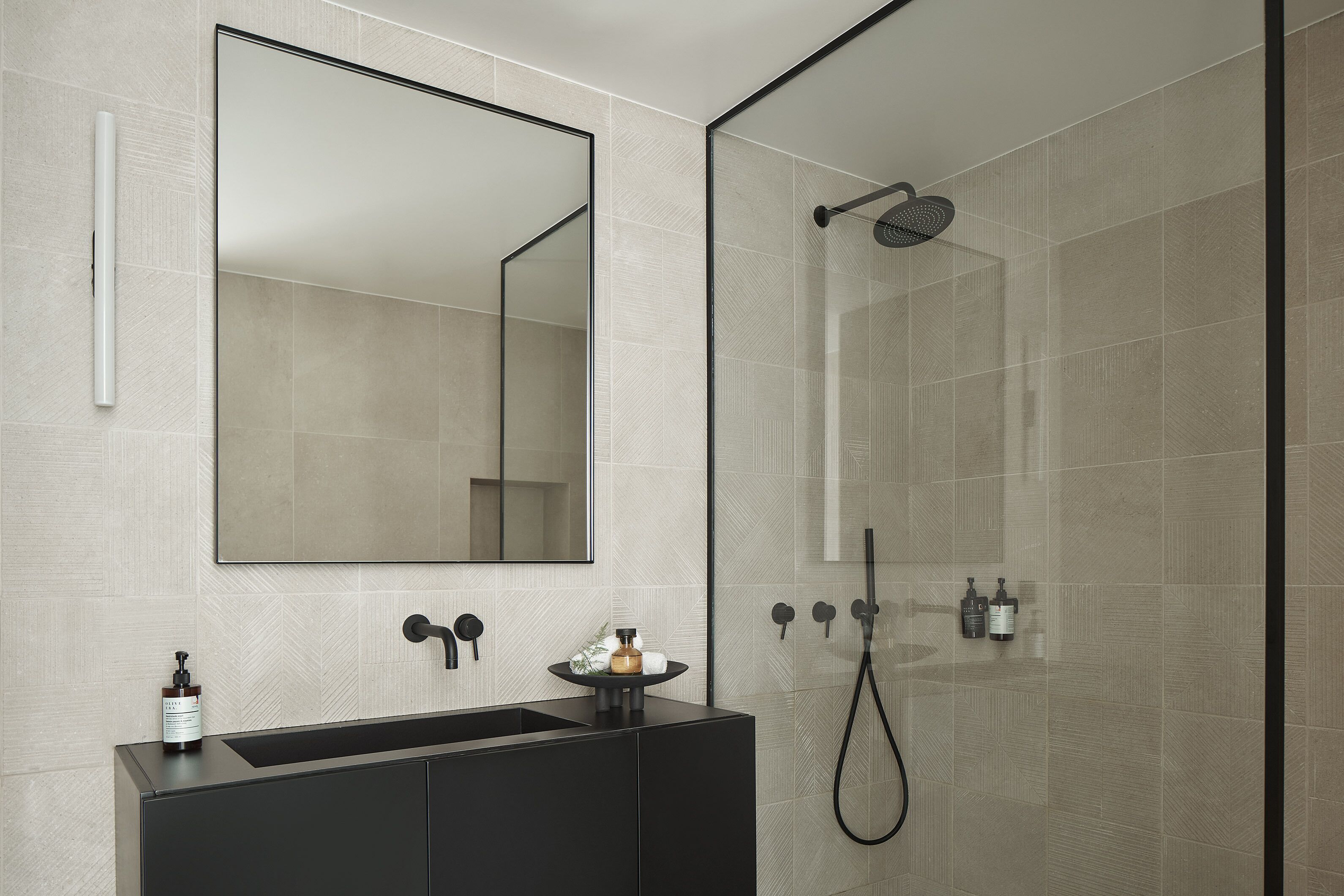 A modern bathroom with a large mirror, a black vanity, and a glass-enclosed shower area.