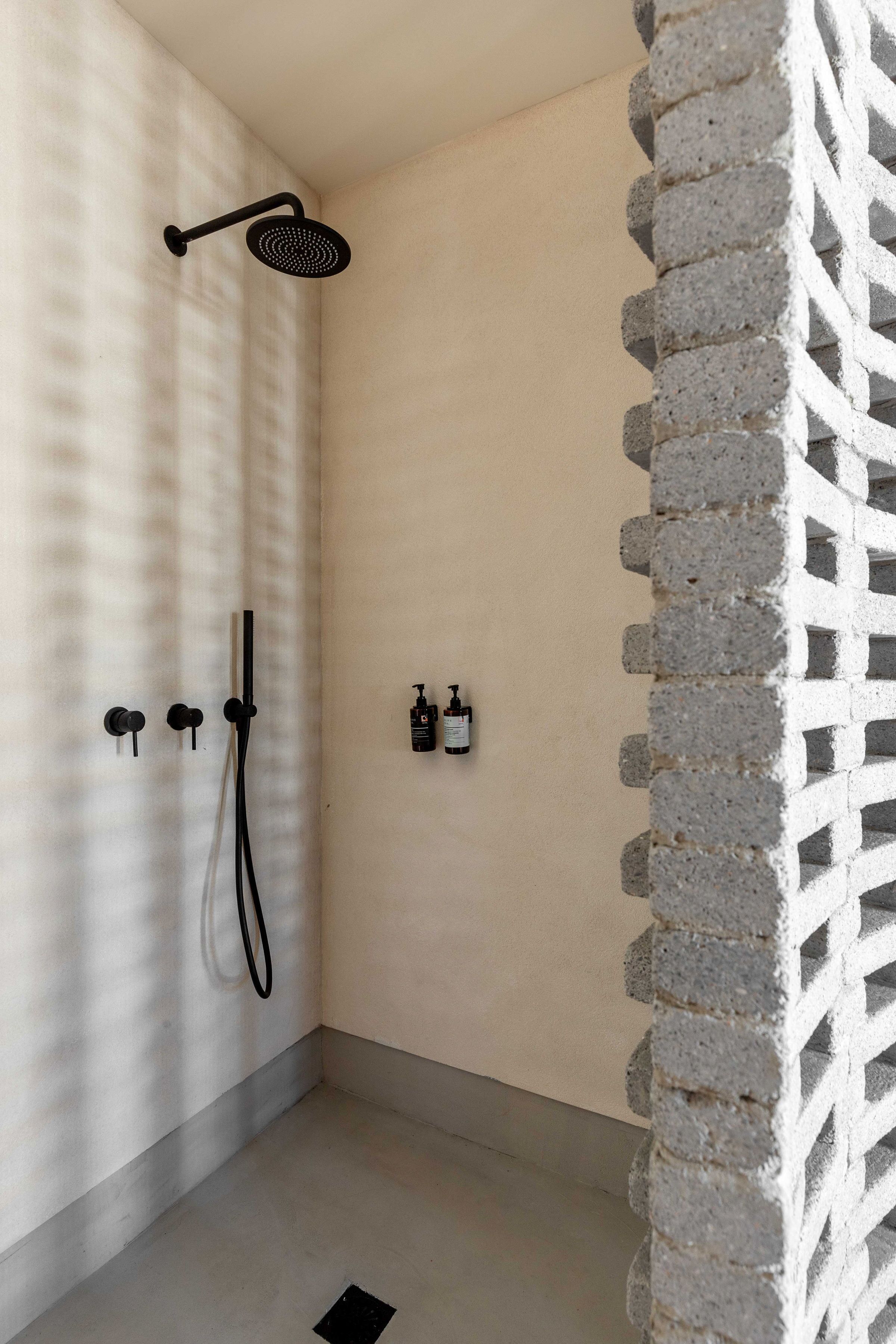 A shower area with a modern design, including a black showerhead and a handheld shower attachment.