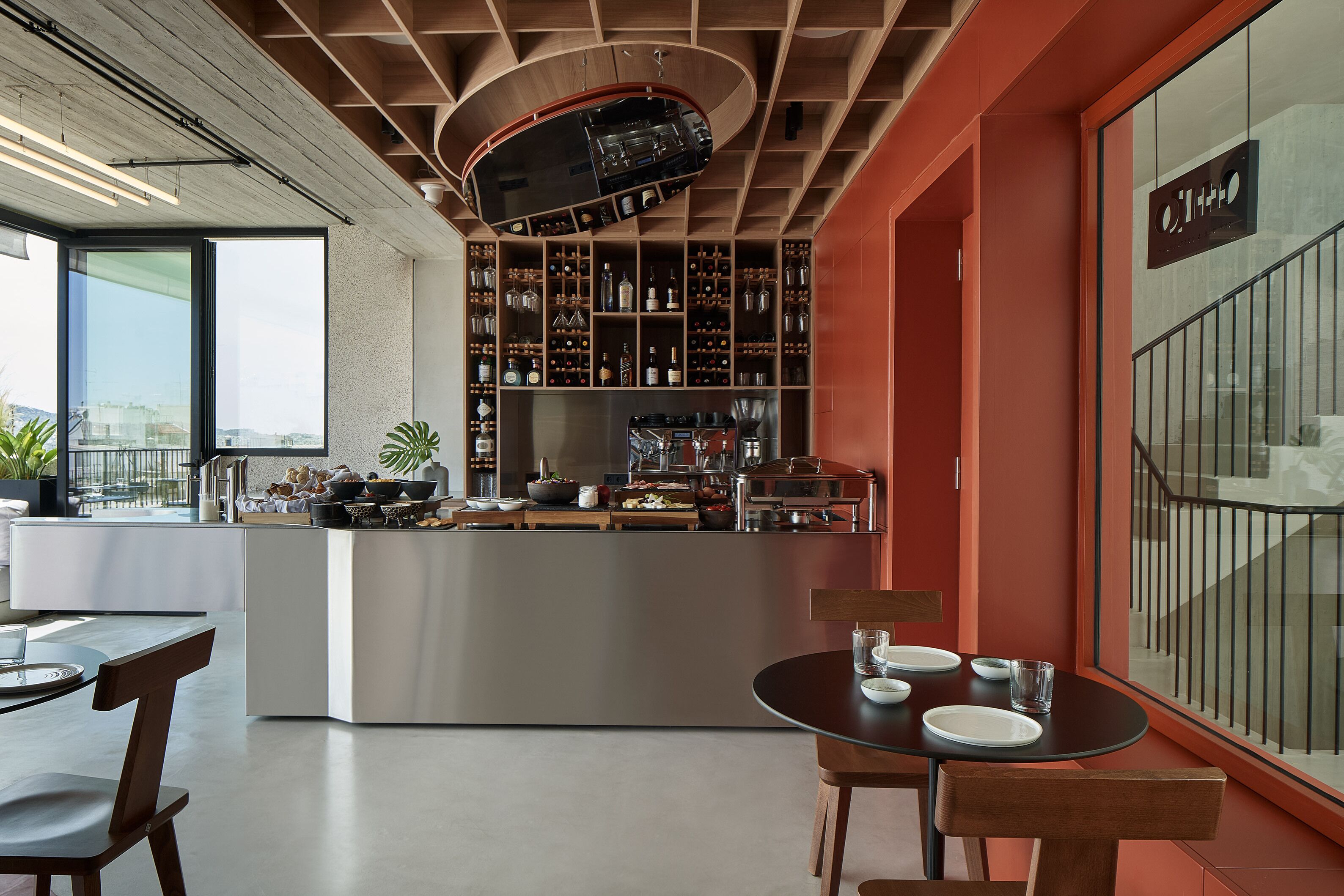 A modern bar area with a curved ceiling, a variety of bottles and glasses, and a dining area with a round table and chairs.
