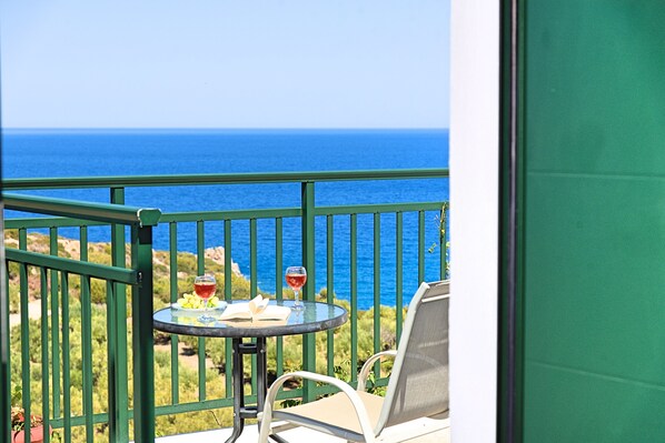 Un balcón con mesa y sillas, con vistas a la costa.