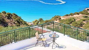 A balcony with a view of the sea, a table with a glass, and a chair. - Istron Homes (Agios Nikolaos)