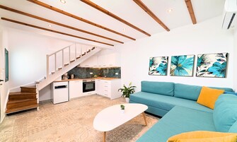 Un espacio habitable moderno con escalera, cocina y un sofá con cojines.