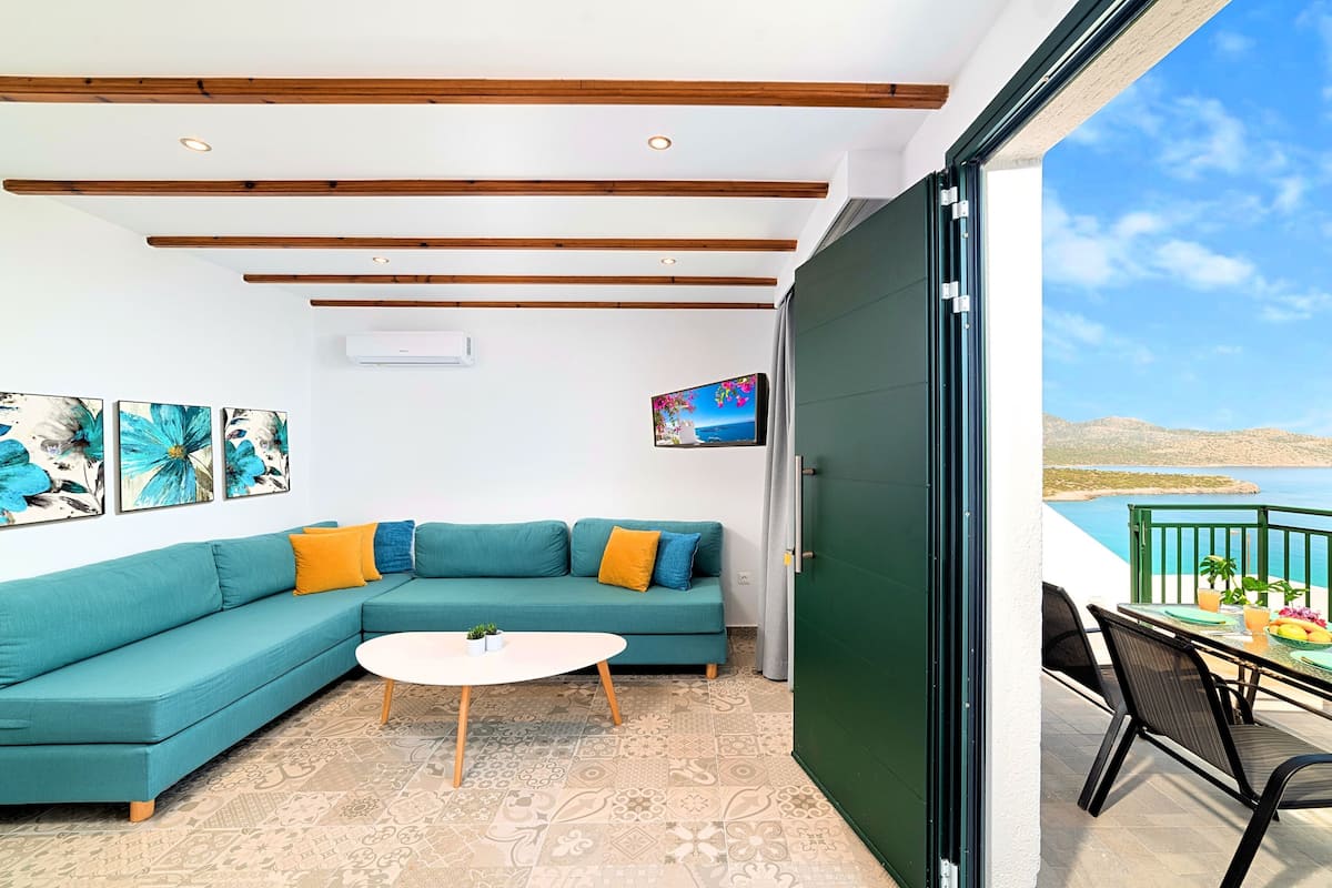 A living room with a teal sofa, a round coffee table, and a TV on the wall.