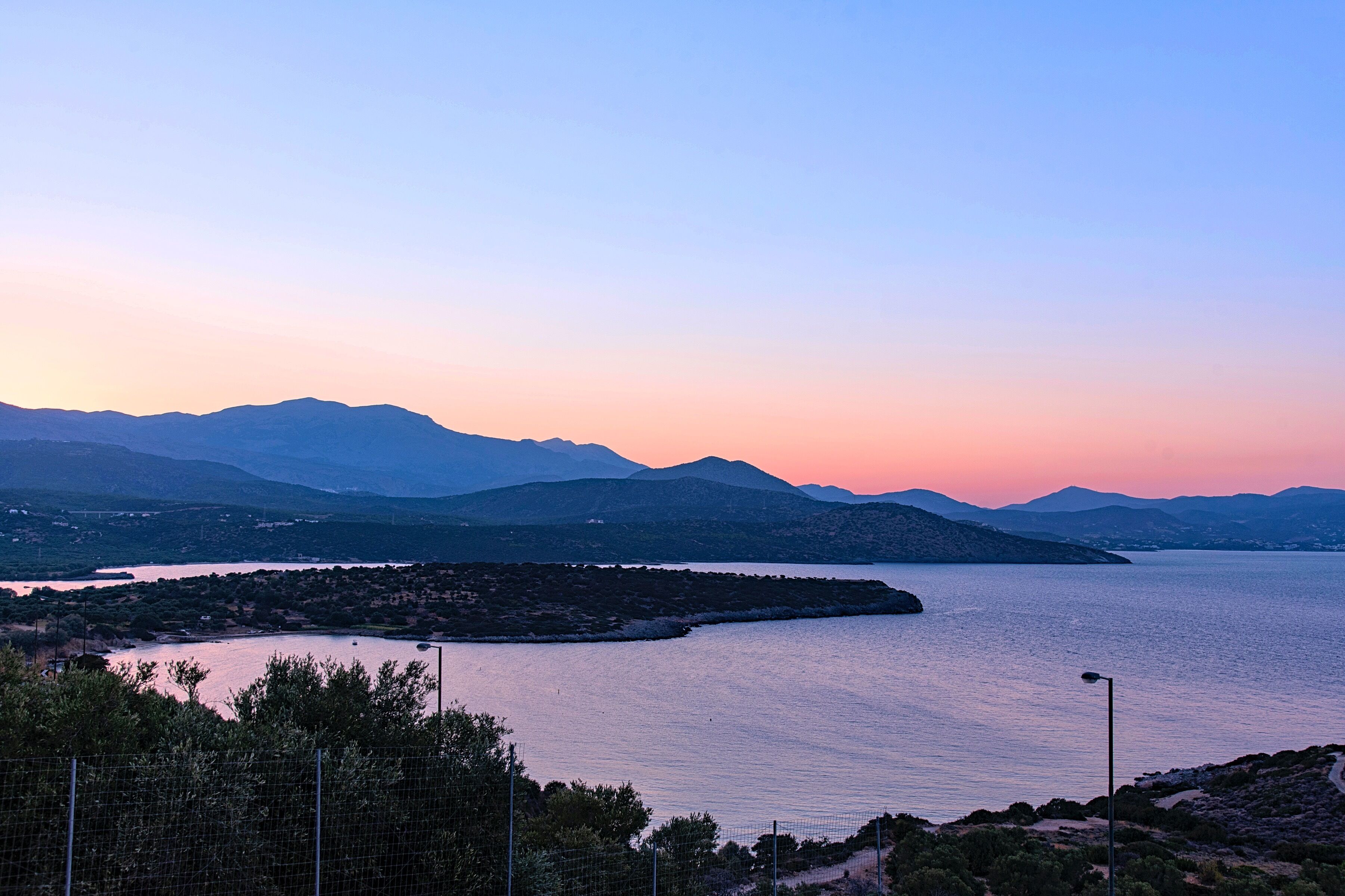 Eine Küstenlandschaft mit Bergen im Hintergrund und einem Gewässer im Vordergrund.