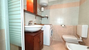 A compact bathroom with a sink, toilet, and washing machine.