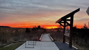 A sunset view from a park pavilion with a concrete pathway leading to it. - Cozy Little Blue Cottage by the Bay (Milford)