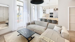 Een moderne woonkamer met een bank, een salontafel en een keuken in de achtergrond.