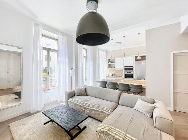 A modern living room with a sofa, a coffee table, and a kitchen area in the background.