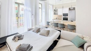 Een moderne hotelkamer met een groot bed, een zithoek, een kitchenette en een eethoek.