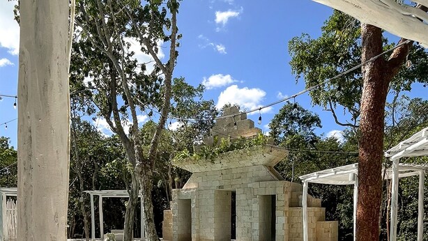 A pool area with a clear blue pool, a person relaxing on a lounge chair, and a pergola structure.