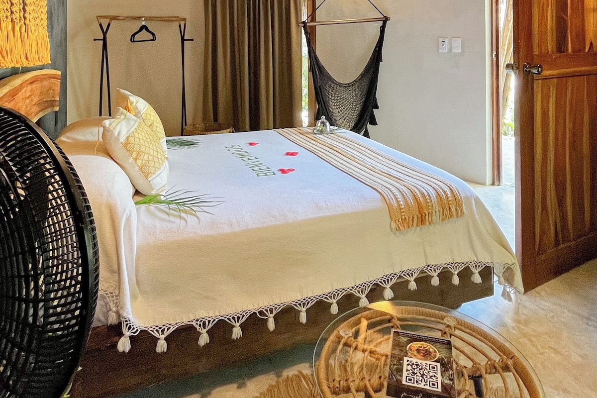 A room with a bed, a hanging chair, a hammock, and a wooden door.