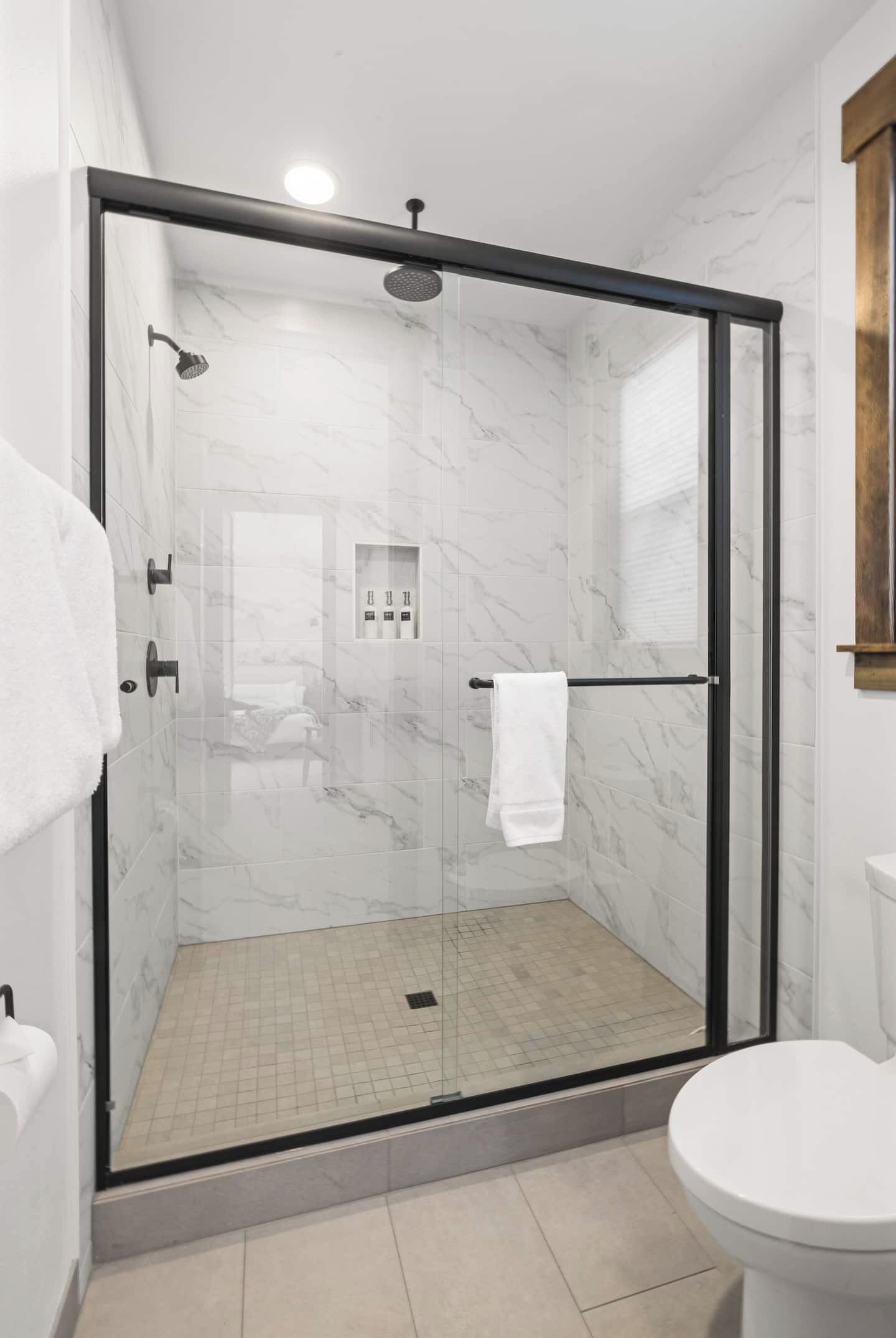 Un bagno moderno con doccia vetrata, un water e un pavimento in marmo.