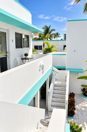 A modern hotel with a white exterior, turquoise accents, a staircase, and a palm tree in the background. - The Marlin Beachside (Hollywood)