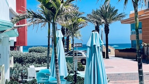 A resort courtyard with palm trees, outdoor seating, and a view of the ocean.