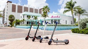 Three electric scooters parked in front of a building with a sign reading "Marlin". - The Marlin Beachside (Hollywood)