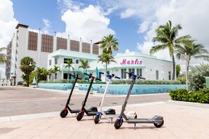 Three electric scooters parked in front of a building with a sign reading "Marlin". - The Marlin Beachside (Hollywood)