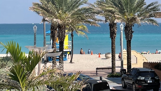 A beach with palm trees, a lifeguard tower, and a clear view of the ocean.