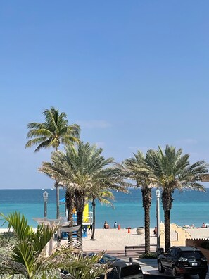 A beach with palm trees, a lifeguard tower, and a clear view of the ocean. - The Marlin Beachside (Hollywood)