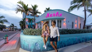 A couple sitting on a curved bench in front of a building with a neon sign reading "Marlin." - The Marlin Beachside (Hollywood)