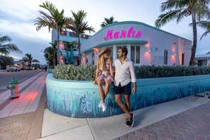 A couple sitting on a curved bench in front of a building with a neon sign reading "Marlin." - The Marlin Beachside (Hollywood)