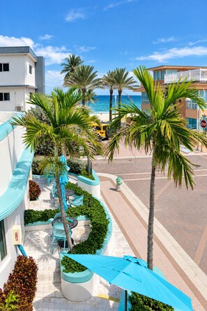 A coastal hotel with a view of the ocean, palm trees, and a yellow vehicle on the street. - The Marlin Beachside (Hollywood)