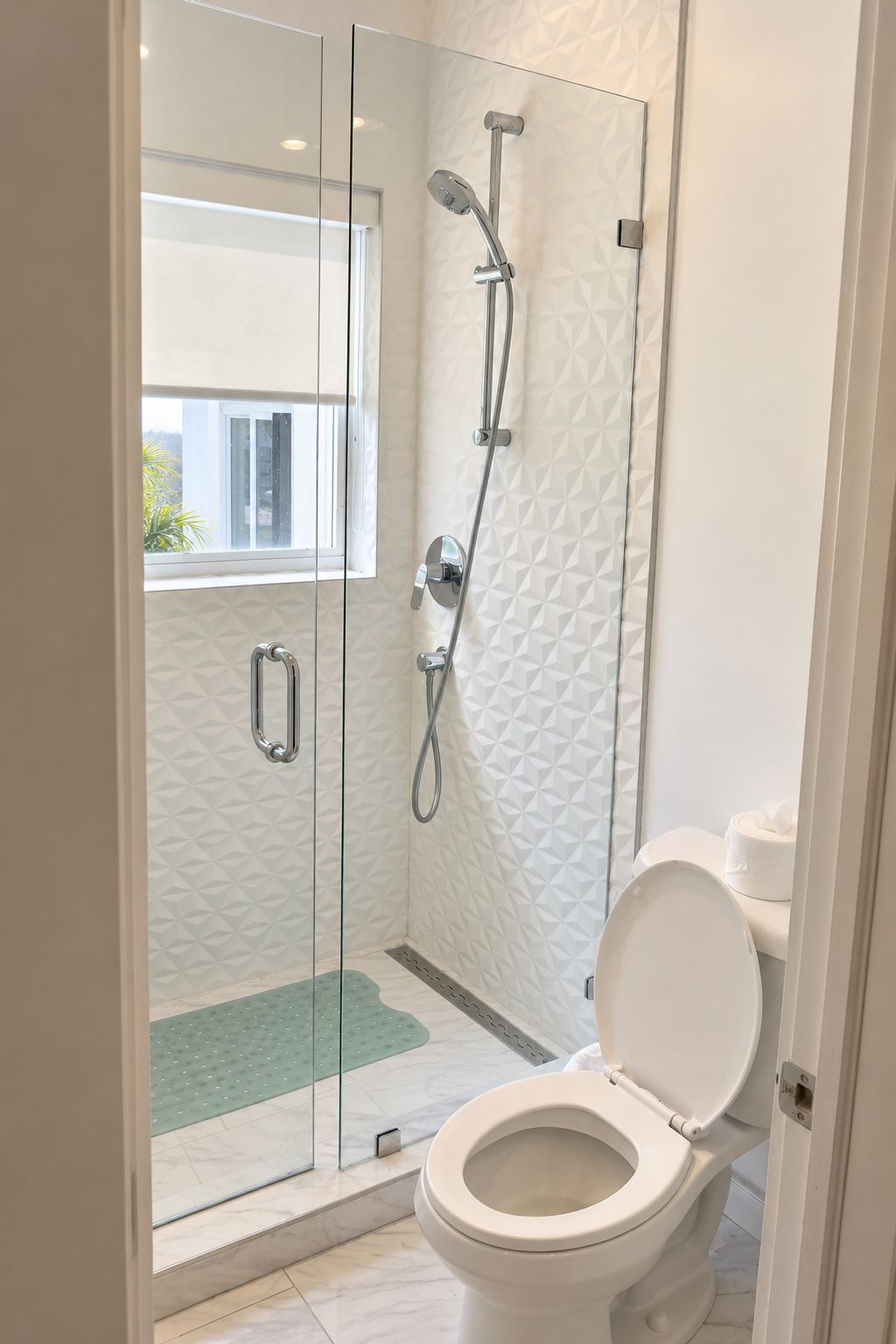 A modern bathroom with a glass-enclosed shower, a toilet, and a patterned wall.