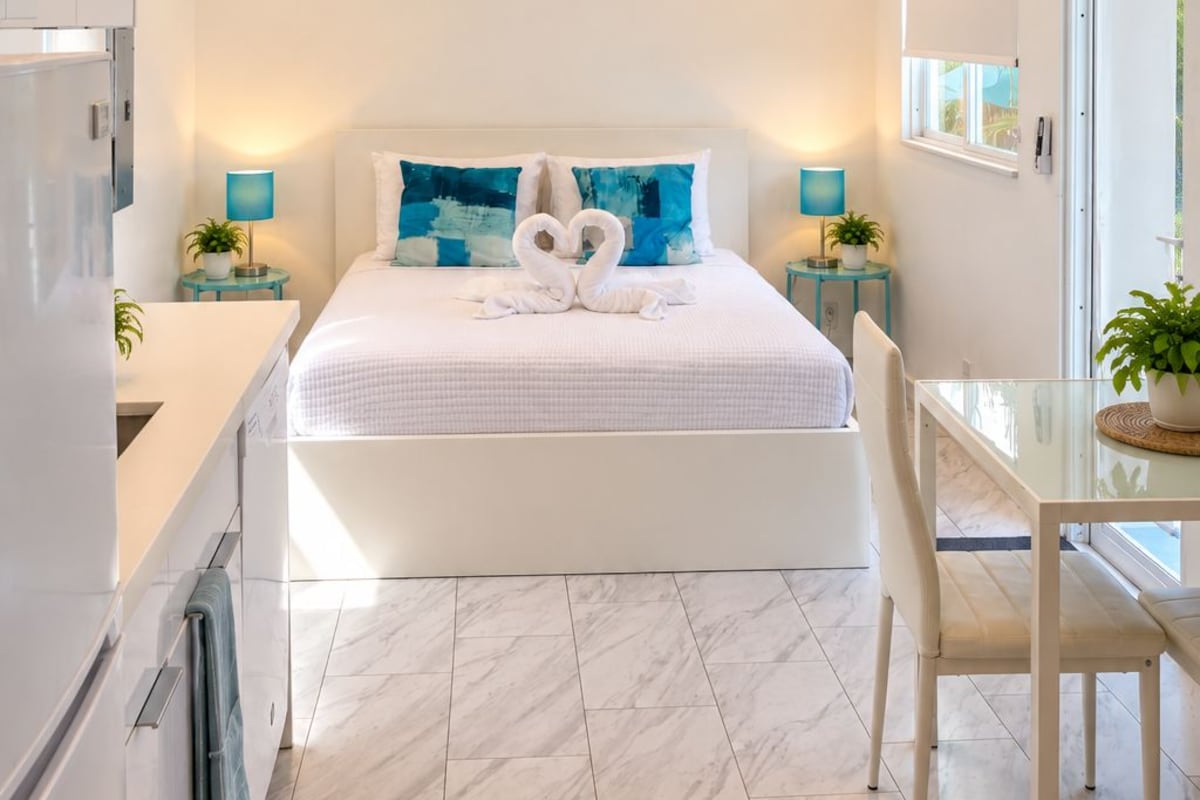 A modern hotel room with a large bed, a desk, and a bathroom.