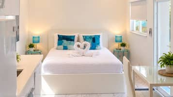 A modern hotel room with a large bed, a desk, and a bathroom.