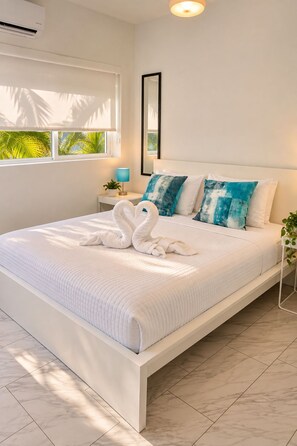 A modern bedroom with a large bed, white bedding, and a tropical view through the window. - The Marlin Beachside (Hollywood)