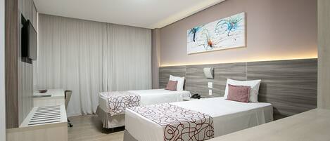 A hotel room with two beds, a desk, a TV, and a painting on the wall.