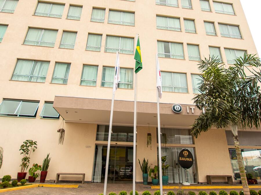 A tall hotel with a flat facade, multiple windows, and a flagpole with flags.