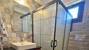 Et moderne badeværelse med en trækommode, en glasbrusekabine og et toilet.