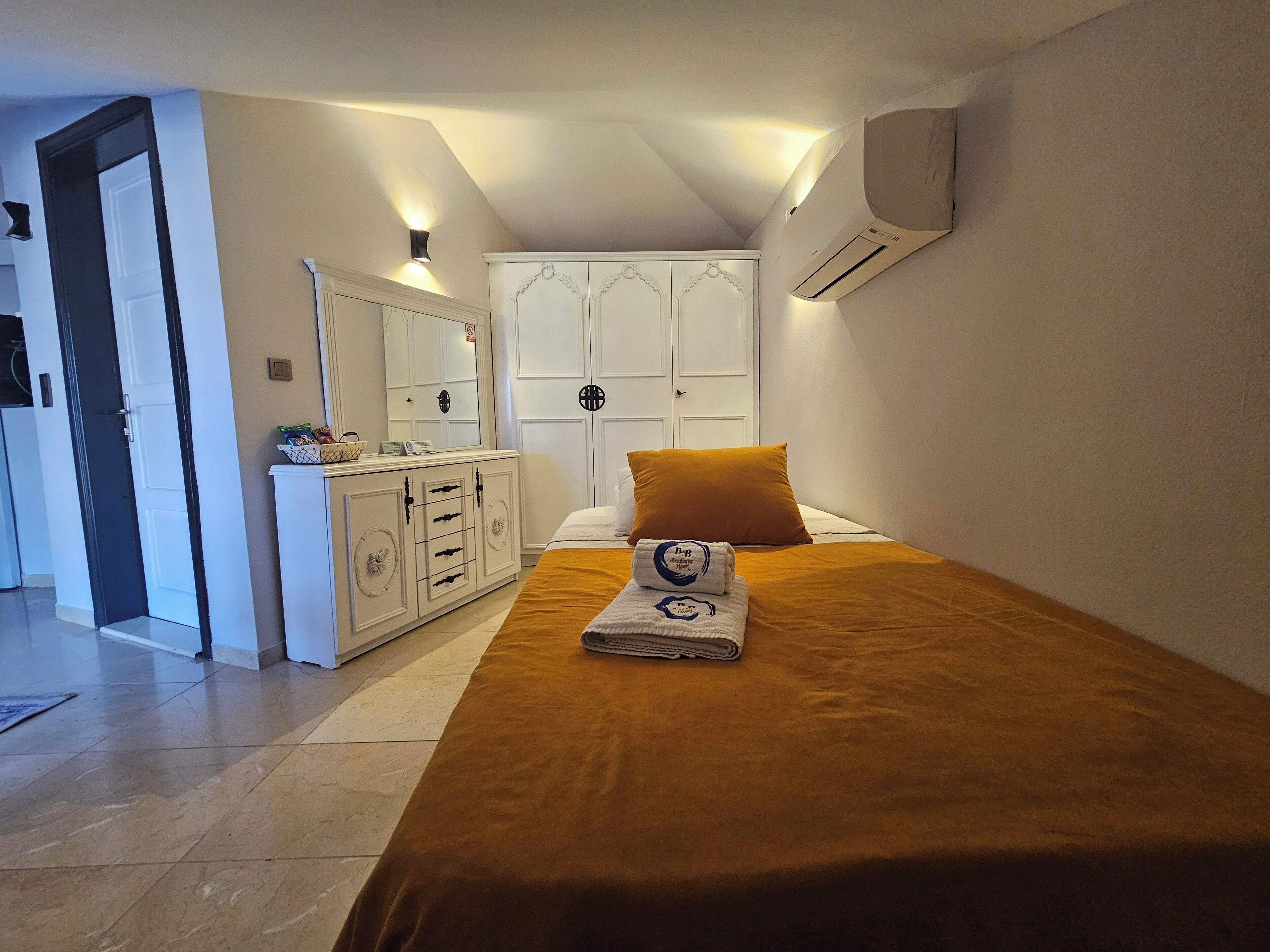 Un dormitorio con una cama, un aparador, un espejo y un equipo de aire acondicionado.