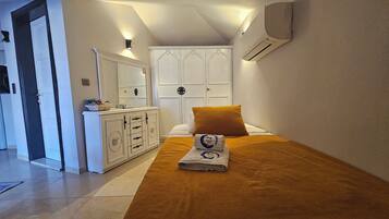 Un dormitorio con una cama, un aparador, un espejo y un equipo de aire acondicionado.