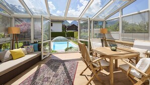 Ein sonnendurchfluteter Raum mit Glasdach, Pool und Sitzgelegenheiten im Freien.