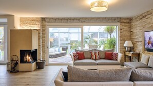 Ein modernes Wohnzimmer mit Kamin, bequemen Sitzmöglichkeiten und großen Fenstern mit Blick ins Freie.