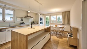 Eine moderne Küche mit einer zentralen Kochinsel, weißen Schränken und einem Essbereich mit Tisch und Stühlen.