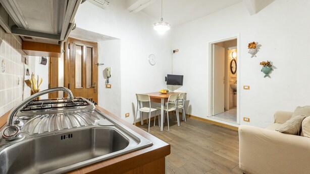 Une cuisine moderne dotée d’un évier en acier inoxydable, de meubles en bois et d’un coin repas avec une table et des chaises.