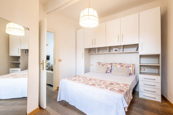 A bedroom with a bed, a wardrobe, and a mirror.