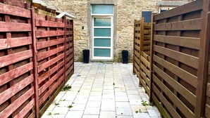 A narrow alleyway with a brick building on one side and wooden fences on the other. - L'appartement d'Houyet (Houyet)