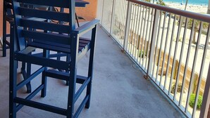 Un balcón con vista a la playa, una mesa y dos sillas.