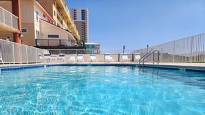 Una piscina cristalina con sillas de descanso y una valla blanca.