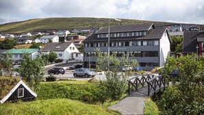 A modern hotel with a flat roof, multiple floors, and a prominent sign. - Hotel Runavik (Runavik)