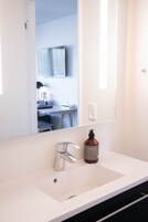Ein Badezimmer mit einem weißen Waschbecken, einem Spiegel und einer Handseife.