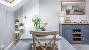 A modern kitchen with a skylight, a dining table with chairs, a wine rack, and a mirror above the counter.