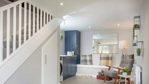 A modern living room with a staircase, a dining area, and a kitchen.