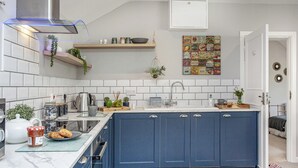 A modern kitchen with a blue island, white tiles, and a variety of kitchen appliances.