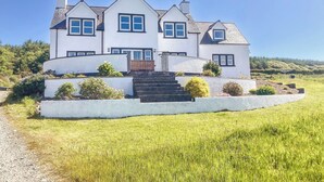 A large, two-story house with a white exterior, multiple windows, and a front staircase leading to the entrance. - 4 bedroom accommodation in Portpatrick, near Stranraer (Portpatrick, near Stranraer)